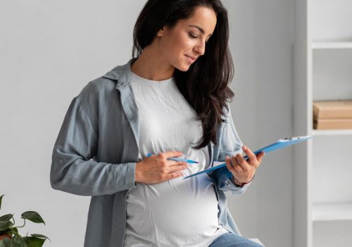 side-view-pregnant-woman-working-from-home-with-clipboard